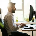 Person with good posture at an ergonomically set up desk in a modern office.